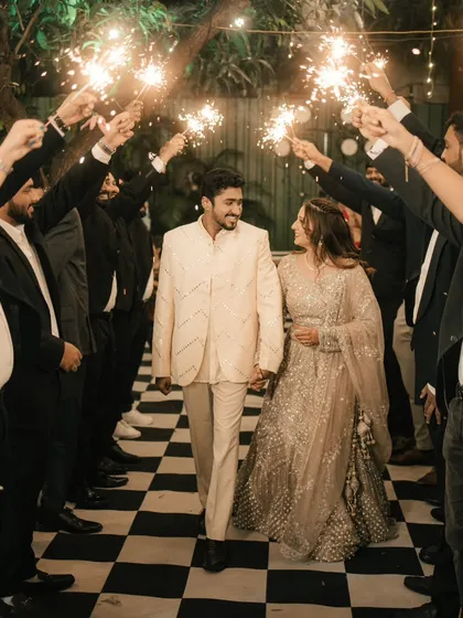 A beautiful, clear shot of the couple making their sparkler entrance, smiling at each other as they walk towards their party.