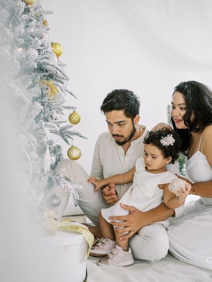 A family gathered around the Christmas tree. The soft, blurry foreground adds an artistic touch to this holiday portrait.