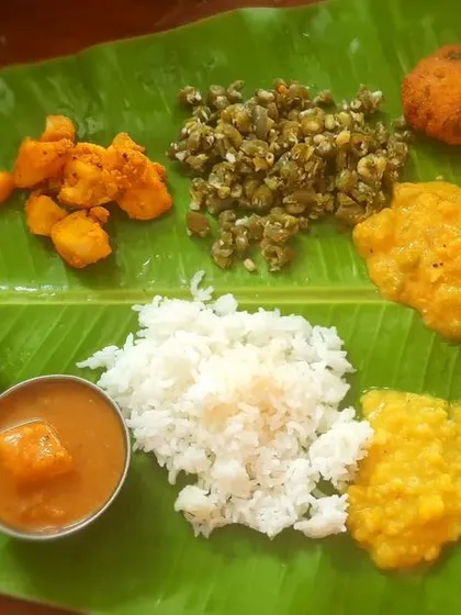A traditional South Indian meal spread, served lovingly on a banana leaf. This is a glimpse of my homely catering service, perfect for pujas and housewarmings. It features a complete satvik menu with items like sambar, poriyal, vada, and payasam.