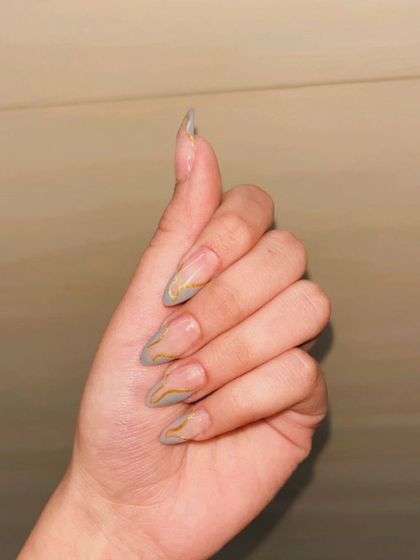 A minimalist abstract design with fine gold and grey lines tracing the edges of long, clear stiletto extensions.