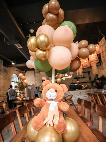 A close-up of a teddy bear centerpiece, showing the mix of balloon colors and textures.
