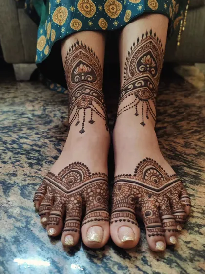 A beautifully symmetric and intricate design for the feet. This pattern features delicate hanging elements around the ankle and detailed work covering the top of the foot, ensuring you look festive from head to toe.