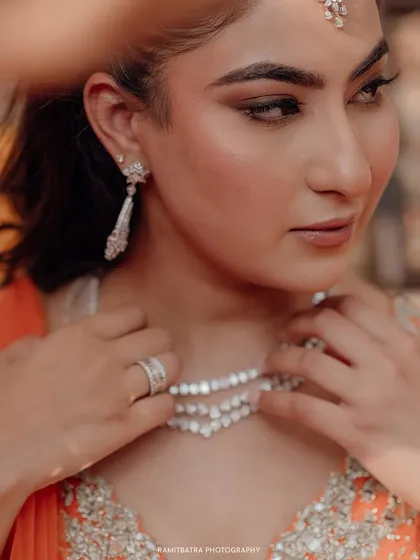 A close-up of the bride adjusting her diamond necklace, a quiet moment of preparation before her engagement.