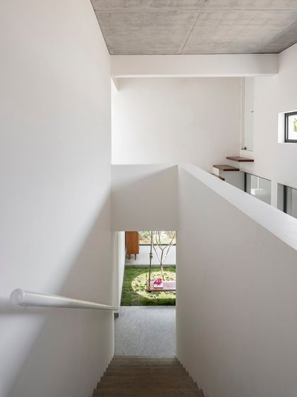 This perspective from the staircase highlights the double-height volume and the simple, clean lines of the architecture. The minimalist aesthetic enhances the spatial quality and draws attention to the natural light.