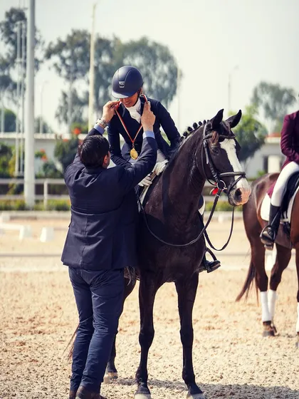 A beautiful moment as a rider receives her gold medal for the Intermediate-1 dressage test. This victory is a proud achievement for both the rider and our entire team.