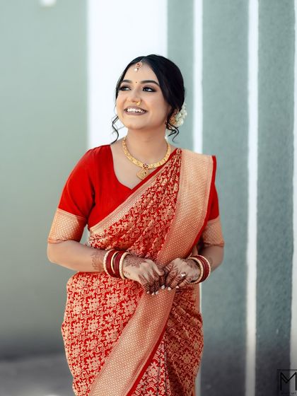 A full-length shot showcasing the simple elegance of a red bridal saree and minimal makeup.