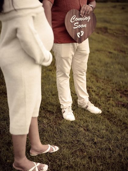 A minimalist and artistic shot focusing on the lower half of the couple, with the dad-to-be holding a "Coming Soon" sign. It's a modern and stylish take on a pregnancy announcement.