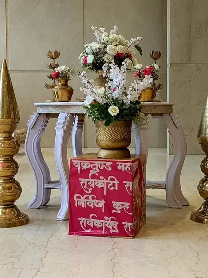 A traditional decor arrangement with brass elements, red roses, and a custom-printed cube featuring a Sanskrit shloka, blending spirituality with beautiful design.