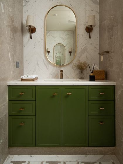 This vanity from "Project Ivy" makes a statement with a bold, solid green cabinet. Set against a neutral marble wall, the color provides a beautiful focal point, complemented by elegant brass hardware and wall sconces.