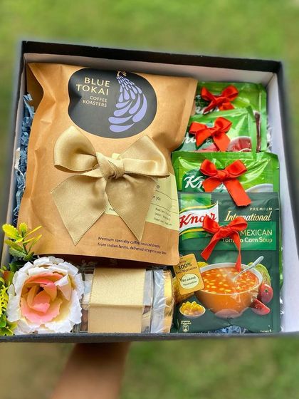 This care hamper is perfect for a coffee lover, featuring a bag of Blue Tokai coffee. It's paired with comforting Knorr soup packets and cheese slices, making it a warm and thoughtful get well gift.