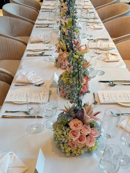 An overhead view of the impeccably set dining table for the Jimmy Choo event, showcasing the symmetrical arrangement of floral centerpieces and place settings.