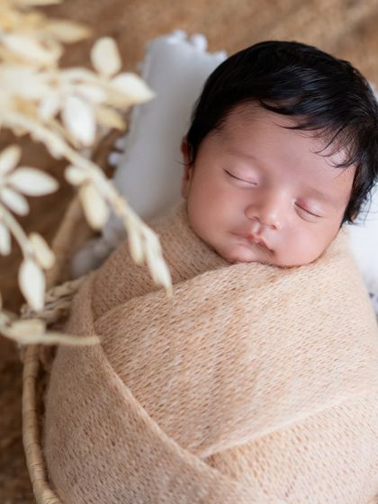 A peaceful newborn portrait, with the baby swaddled in a soft beige wrap.