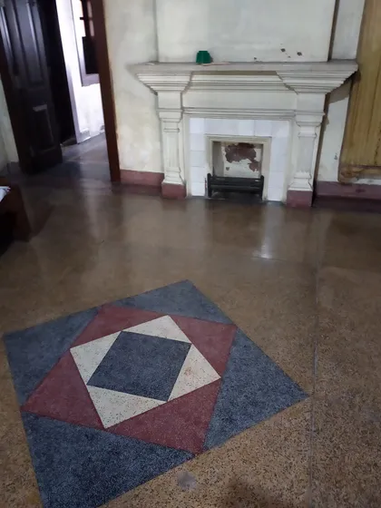 An original fireplace with its geometric terrazzo floor inlay, a quintessential Art Deco detail that is central to the building's character.