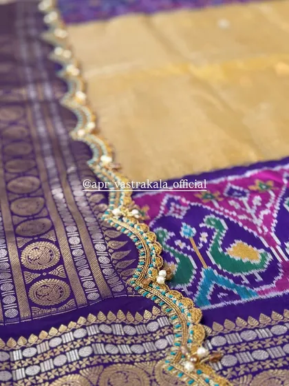 A delicate scalloped border in turquoise and gold on a purple Patola saree, demonstrating fine finishing.