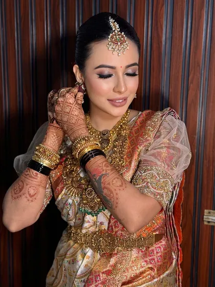 A candid moment of the bride adjusting her earring. This shot highlights the intricate details of her henna and the flawless makeup.