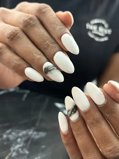 A crisp white manicure with a smoky black and silver glitter accent nail. The abstract design adds an edgy touch to the clean white base.