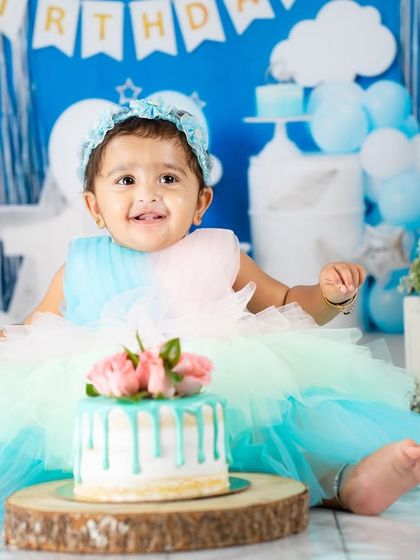 A princess in a sea of blue. This beautiful setup with a drip cake and matching dress creates a stunning portrait for a first birthday.