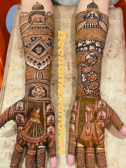 This is a full bridal design with bride and groom portraits on the palms. The arms are decorated with intricate jharokha windows and peacock motifs.