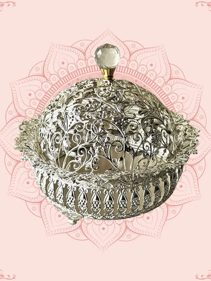 A stunning silver-domed container with intricate cutwork. This piece is ideal for serving dry fruits or sweets and makes for a luxurious and traditional gift.