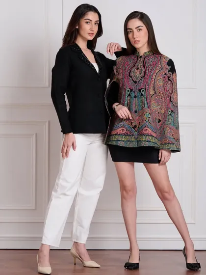 A lookbook shot featuring two models in contrasting winter capes. This allows customers to see different styles from the same collection side-by-side against a clean studio background.