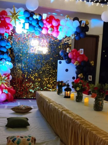 A casino-themed Diwali party setup on a terrace. The decor includes a gold sequin wall, a balloon arch, and low seating with cushions.