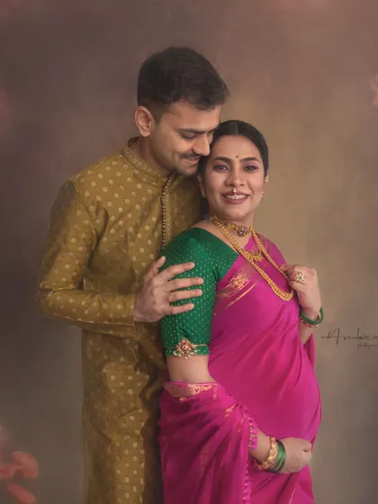 An intimate and tender moment between the expecting parents. This portrait captures their love and excitement, framed by the soft, artistic elements of the studio setup.