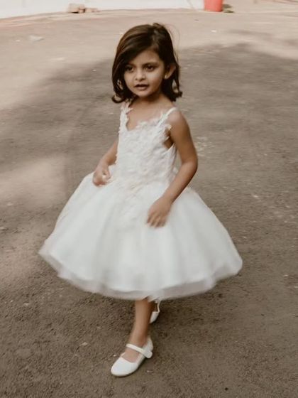 A candid shot of a little flower girl on the move. Her white tulle dress is designed to be light and easy to wear, so she can navigate her important duties with confidence and a smile.