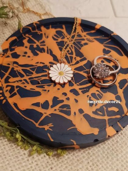 One of our favorite custom pieces, a round coaster with a navy blue base and a vibrant orange splatter effect.