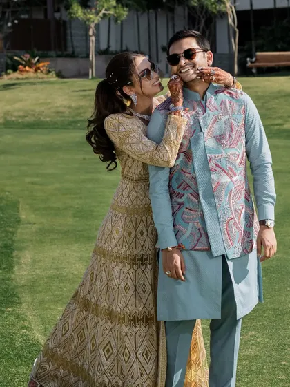A playful moment between the bride and groom during their welcome lunch. Her golden sharara set by Abhinav Mishra is both elegant and comfortable for a daytime event.