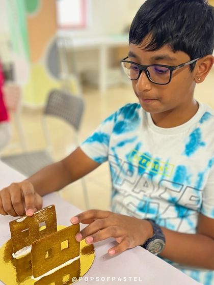 The first step to a delicious masterpiece. This young participant carefully assembles the walls of his gingerbread house with icing.