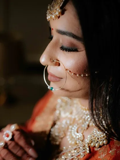 A close-up profile of a bride, highlighting her elegant nose ring and the serene expression on her face. This shot focuses on the beauty of the bridal details.