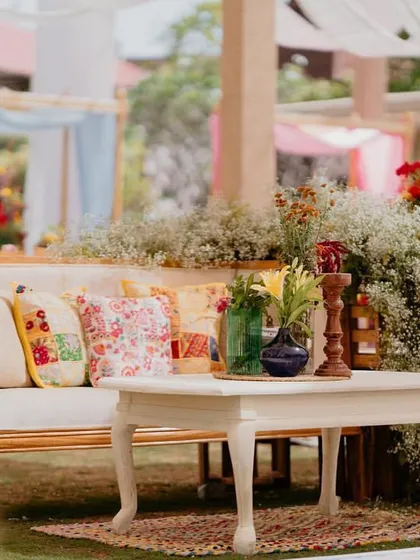 A lounge seating area at the 'Rajasthani Folklore' Mehendi, surrounded by baby's breath and colorful flowers.