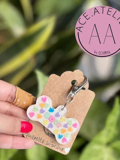 A cute, bone-shaped dog tag with colorful hearts. A fun and practical accessory for your furry friend.