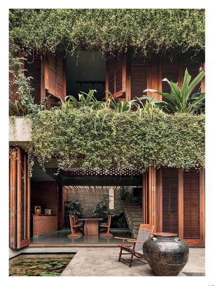 A full shot of the home's facade from the garden, as seen in the magazine. The abundant creepers and planters on the balconies were designed to soften the structure and integrate it completely with the surrounding landscape.