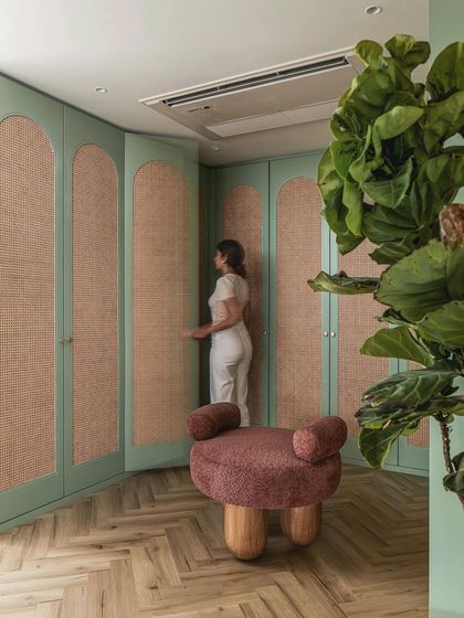 The walk-in closet in the master suite features sage green wardrobes with cane inserts, adding a natural, textural element to the space.