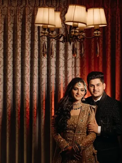 A formal and elegant portrait of the couple against a rich, textured backdrop. The lighting and their pose give this image a classic and timeless quality.