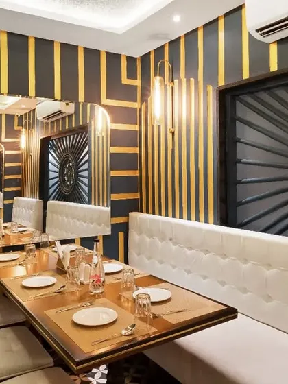 The dining area of The Rogan, where infinity mirrors create a dazzling visual effect. The combination of white banquettes, dark walls, and gold accents results in a glamorous and sophisticated ambiance.