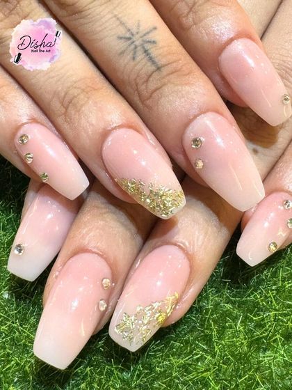 A glamorous set of baby boomer nails with gold glitter and rhinestone accents.