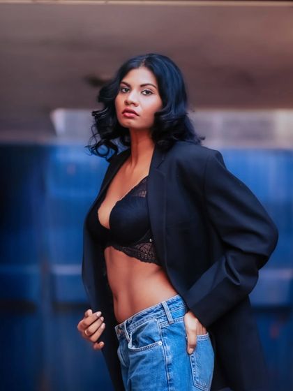 A close-up shot that captures her confident expression and the stylish details of her outfit against a vibrant blue industrial door.