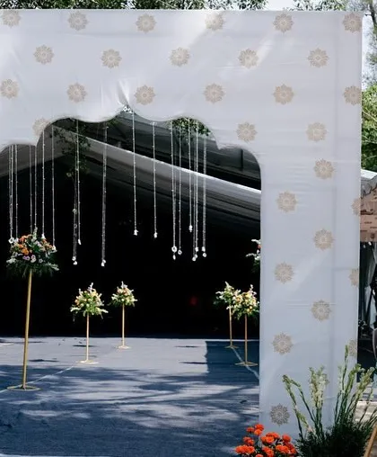 A welcoming archway for an outdoor wedding, designed with a custom print and delicate hanging flowers, setting the tone for a beautiful celebration.