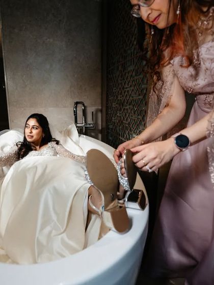 Finding innovative ways to get ready! A fun and quirky shot of the bride getting her shoes on in a bathtub to protect her dress.