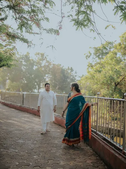 A walk across a bridge, surrounded by morning light. This beautiful, atmospheric shot captures the couple in their elegant ethnic wear during an outdoor pre-wedding session.