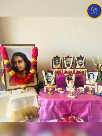 A beautiful altar setup for Guru Purnima, with a large portrait of Paramhansa Yogananda garlanded in red. The vibrant colors and fresh flowers are our humble offering of love and gratitude to the gurus.