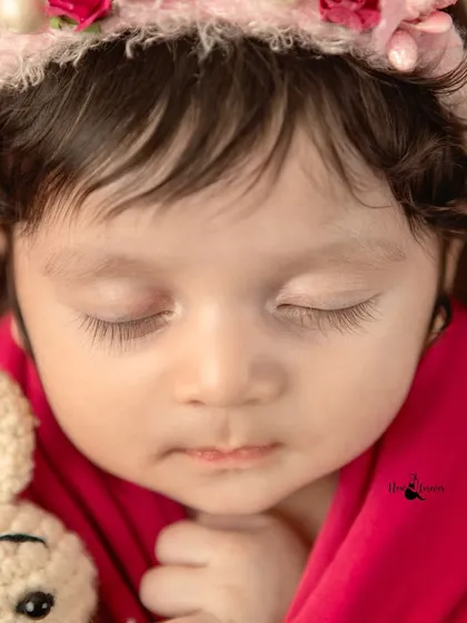 A close-up of a sleeping newborn's face, with long eyelashes and perfect features. These portraits focus on the pure beauty of your new baby.
