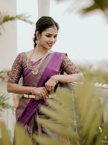 A bride posing on a balcony, framed by green leaves, creating a natural and fresh portrait.