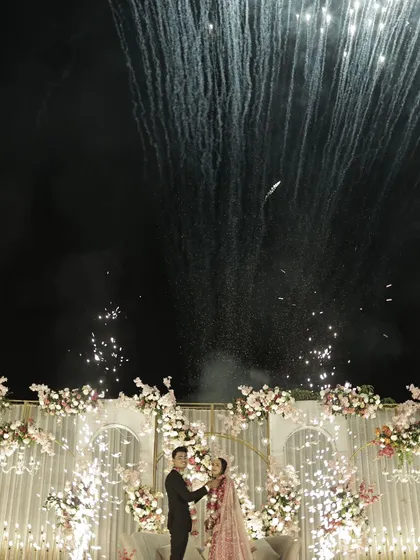 A spectacular shot of the couple on their reception stage, framed by an explosion of fireworks.