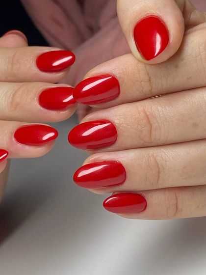 A vibrant, glossy red manicure on elegant almond-shaped nails. This timeless color is a staple, and our technique ensures it looks stunning for weeks.