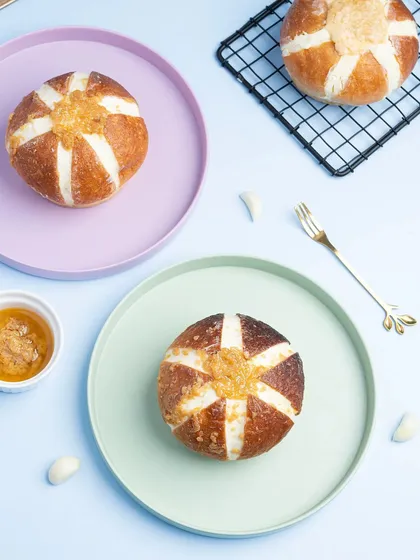 Korean cream cheese garlic buns arranged on pastel-colored plates. The top-down angle and soft colors create a trendy, aesthetic look for social media.