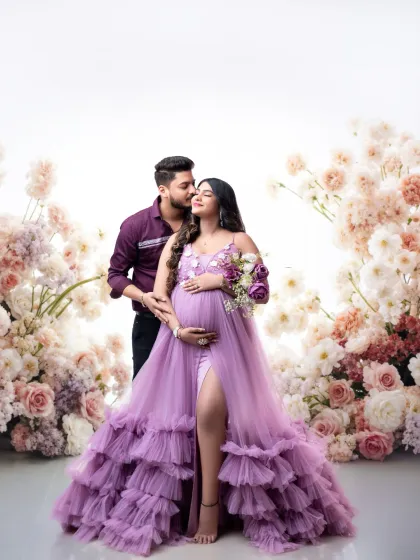 A fairytale romance. The couple is surrounded by a stunning arch of flowers, the father-to-be embracing his partner in her gorgeous lavender gown.
