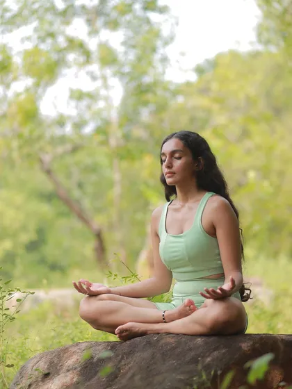 Meditating on a rock in nature. This image accompanies a journaling exercise I practice called 'roses, thorns, and buds,' a technique to reflect on the past month and set intentions for the future.